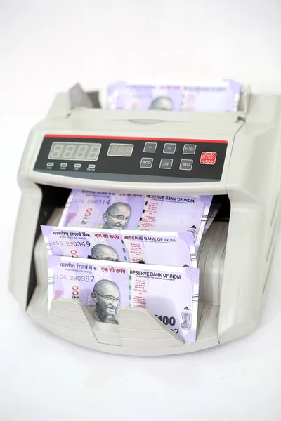 Yeni Hint 100 rupi banknotları ile elektronik para sayacı. Beyaz arka planda yalıtılmış.