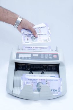 Nakit sayma makinesinde Hint para koyarak bir el fotoğrafı. Beyaz arka planda yalıtılmış.
