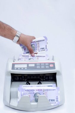 Nakit sayma makinesine Hint para birimini koyan bir elin portresi. Beyaz arka planda yalıtılmış.