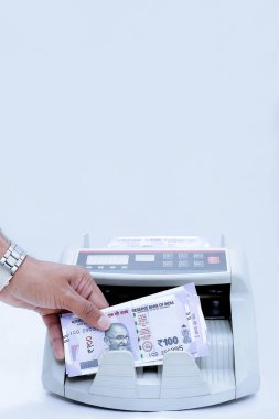 Adam el resmi nakit sayma makinesine yeni Hint para notları koyarak. Beyaz arka planda yalıtılmış.
