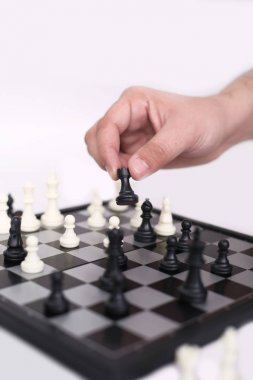 Adam satranç oynuyor ve elinde piyon tutuyor. Beyaz arka planda yalıtılmış.