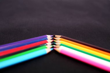 Satırda güzel ahşap renkli kalemler. Siyah arka planda yalıtılmış.