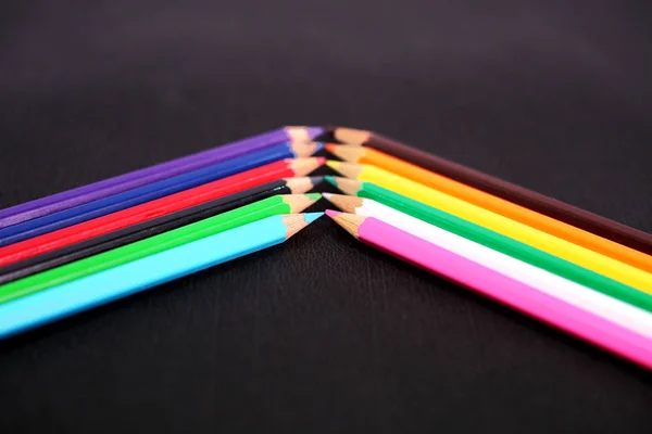 Picture of beautiful wooden colored pencils in row. Isolated on the black background.