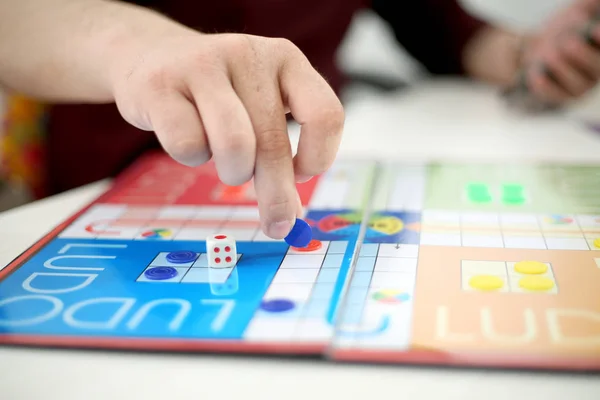 Ludo oyunu oynayan adamın resmi. Beyaz arka planda yalıtılmış..