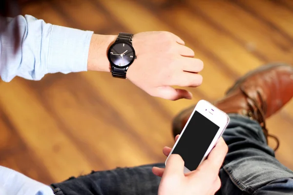 Cep telefonu yla çalışan ve el saati takan adam. Beyaz arka planda yalıtılmış.