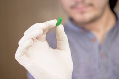 Elinde kapsül ilacı tutan bir adamın resmi. Beyaz arka planda yalıtılmış.