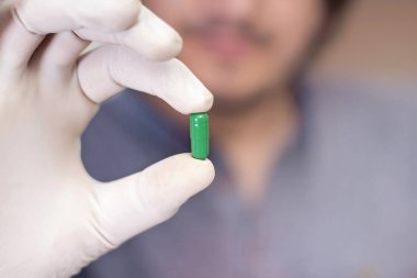 Elinde kapsül ilacı tutan bir adamın resmi. Beyaz arka planda yalıtılmış.