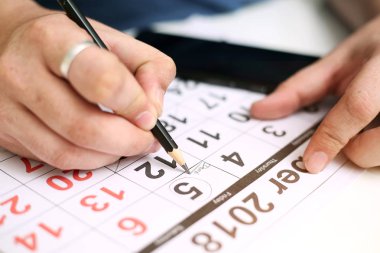 Picture of Man holding Calendar and marking on date. Isolated on white background. clipart