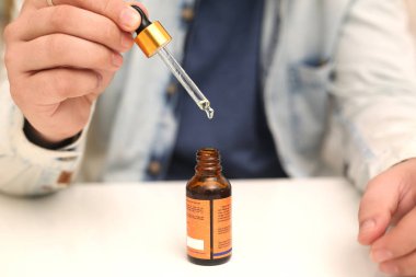 Elinde tutan ilaç şişesini bırakan bir adamın resmi. Beyaz arka planda yalıtılmış.