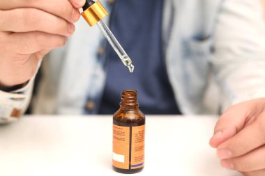 Elinde tutan ilaç şişesini bırakan bir adamın resmi. Beyaz arka planda yalıtılmış.