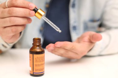 Elinde tutan ilaç şişesini bırakan bir adamın resmi. Beyaz arka planda yalıtılmış.