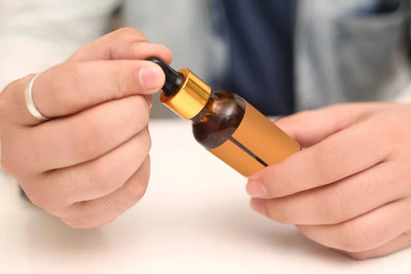 Elinde tutan ilaç şişesini bırakan bir adamın resmi. Beyaz arka planda yalıtılmış.