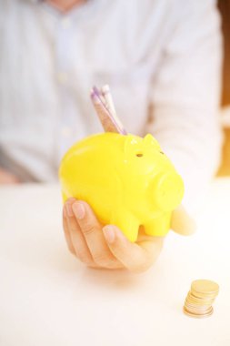  Sarı domuz kumbarasına para yatıran birinin resmi. Arkaplanda izole.