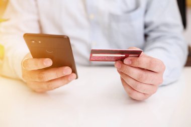 Akıllı telefon kullanan ve internetten alışveriş yapan bir adamın resmi. Çevrimiçi ödeme kavramı.
