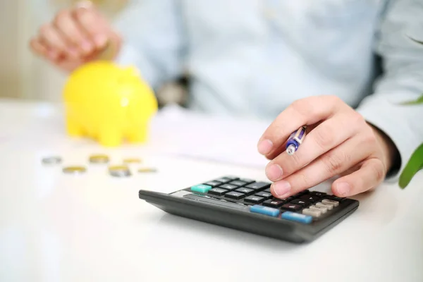  Sarı domuz kumbarasına para yatıran birinin resmi. Arkaplanda izole.