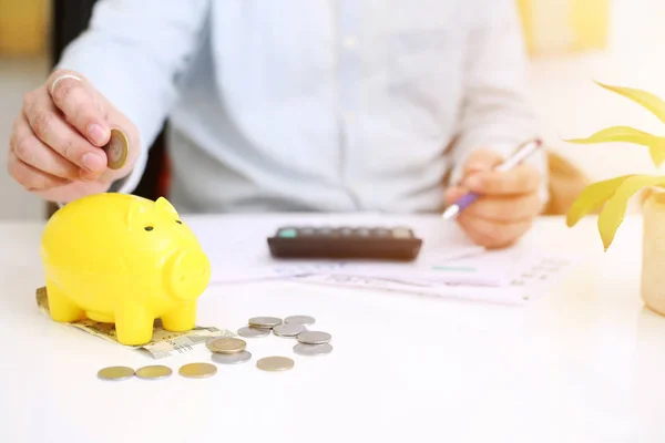  Sarı domuz kumbarasına para yatıran birinin resmi. Arkaplanda izole.