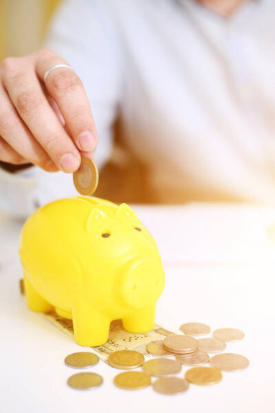  Фото человека, кладущего деньги в желтую копилку. Изолированный на заднем плане
.