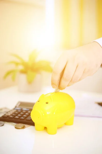  Sarı domuz kumbarasına para yatıran birinin resmi. Arkaplanda izole.