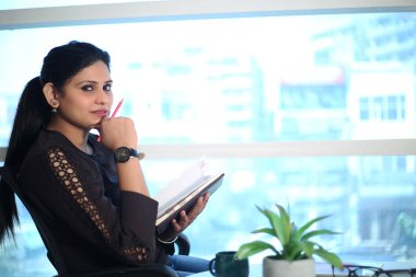 Masada oturan genç iş kadını ofiste bilgisayar kullanıyor, modern yönetici kız..