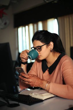 Masada oturan genç iş kadını ofiste bilgisayar kullanıyor, modern yönetici kız..