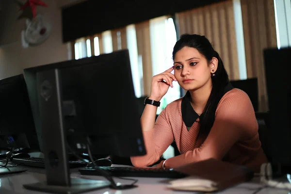 Masada oturan genç iş kadını ofiste bilgisayar kullanıyor, modern yönetici kız..