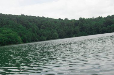 Kuzey Kafkasya eteklerinde mavi gölün berrak su yüzeyi, yeşil yoğun taç
