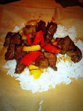 Biftek hamuru ve sebzeli pilav tabağı kağıdıyla kaplanmış, açık hava restoranının barında servis ediliyor.