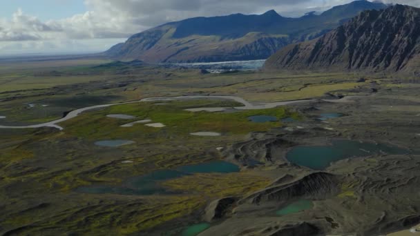 Vista aérea de los flujos de agua que encuentran su camino a través de prados verdes en un valle — Vídeo de stock