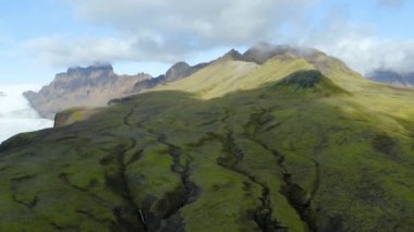 İzlanda 'da büyük ve güzel bir buzulun yanında yeşil dağlar.