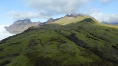 İzlanda 'da büyük ve güzel bir buzulun yanında yeşil dağlar.