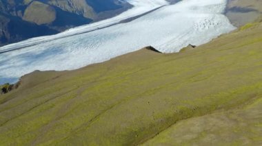 İzlanda 'daki buzulların önünde güzel yeşil dağlar var. 