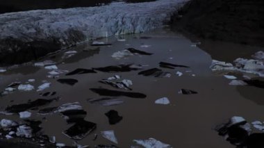 Gün batımında İzlanda 'da eriyen buzdağlarıyla dolu bir gölün üzerinde uçmak..