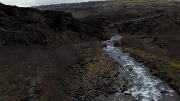 岩の多い山々、アイスランドの間に小さな川を巻きの空中ビュー. — ストック動画