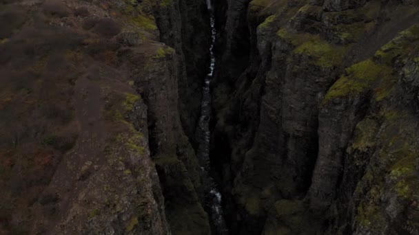 Antenn av stenig grön Fjadrargljufur Canyon på Island med en bäck vattenfall — Stockvideo