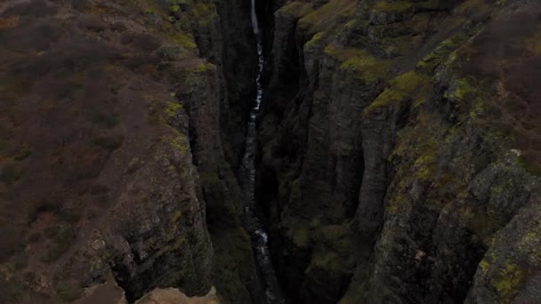 Antenn av stenig grön Fjadrargljufur Canyon på Island med en bäck vattenfall — Stockvideo