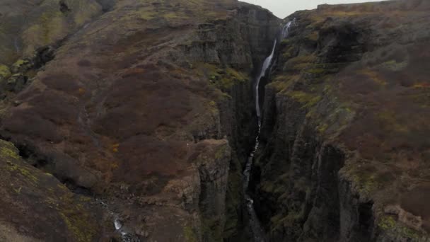 Antenn av stenig grön Fjadrargljufur Canyon på Island med en bäck vattenfall — Stockvideo