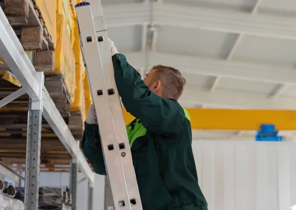 A young worker climbs the stairs leading up to the location of the finished product. Work in the warehouse to move the cargo.