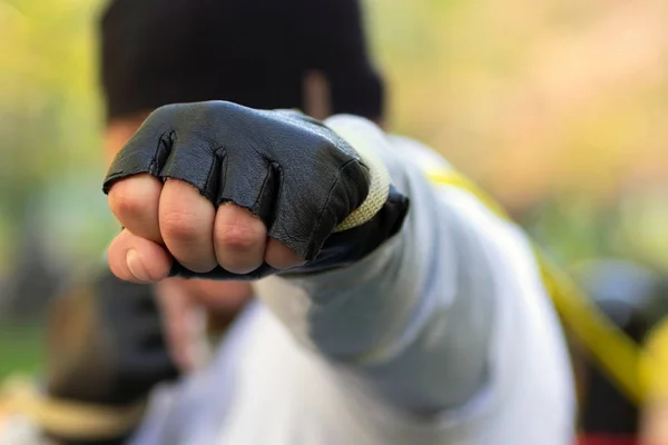 El boxeador golpea con el puño en un guante protector contra el objetivo. En su puño sujetado con gran goma del entrenador . — Foto de Stock