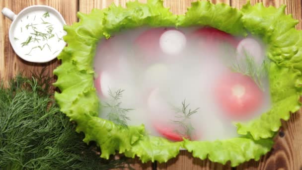 在用生菜装饰的菜里 有切碎的西红柿 黄瓜和萝卜 上面覆盖着晨雾 微风吹去盘子里的雾 让你加入牛奶酱 — 图库视频影像