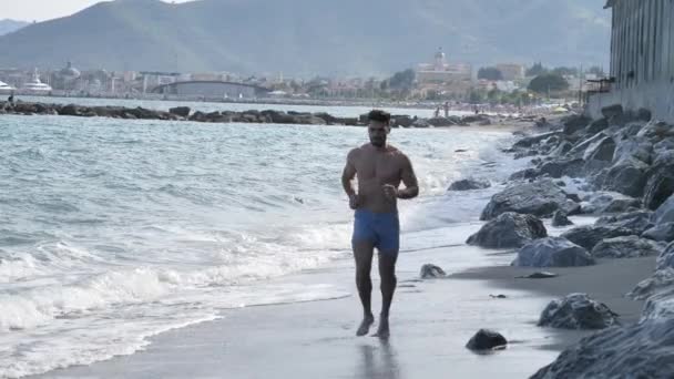 Ung man på stranden kör — Stockvideo