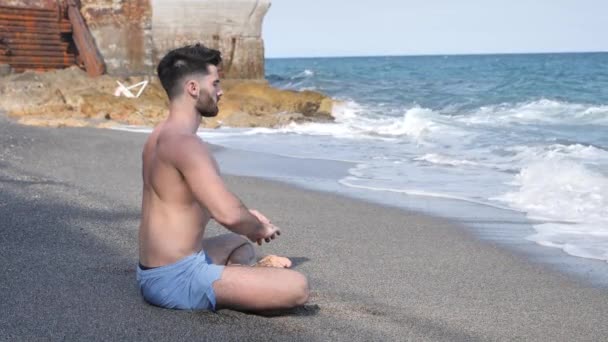 Ung man mediterar eller gör yoga övning av havet — Stockvideo