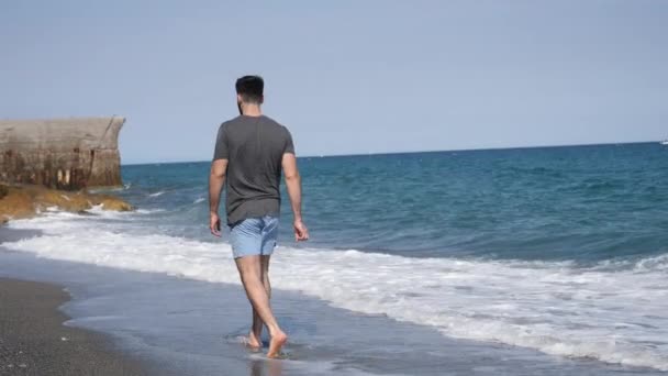 Young athletic man walking at the beach — Stock Video