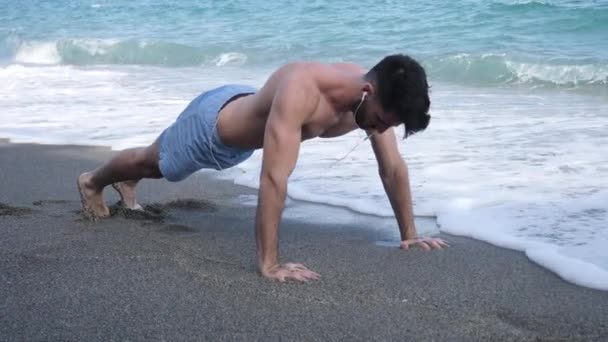 Joven haciendo ejercicio, haciendo flexiones en la playa — Vídeo de stock