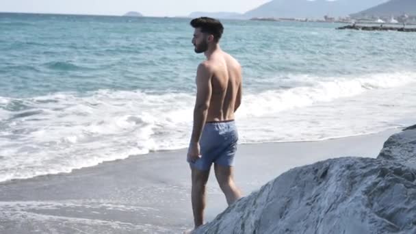 Giovane uomo che cammina da solo su una spiaggia — Video Stock