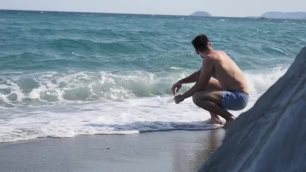 Jovem sentado numa praia sozinho e solitário — Vídeo de Stock