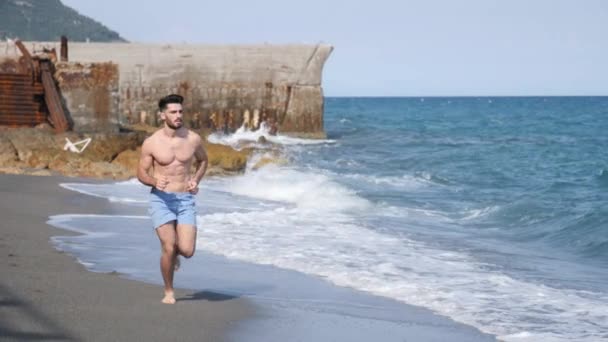 Jonge man uit te oefenen, joggen en lopen op strand — Stockvideo