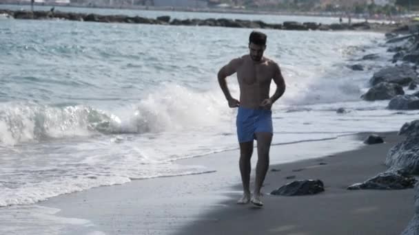 Giovane uomo che si allena, fa jogging e corre sulla spiaggia — Video Stock