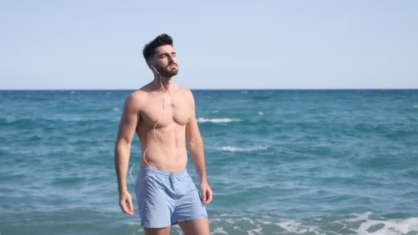 Muskulös ung man på stranden njuter av frihet — Stockvideo