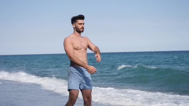 Jonge man doen stretching oefening op strand — Stockvideo