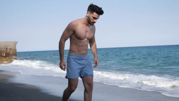 Молодой человек занимается спортом, отжимается на пляже — стоковое видео